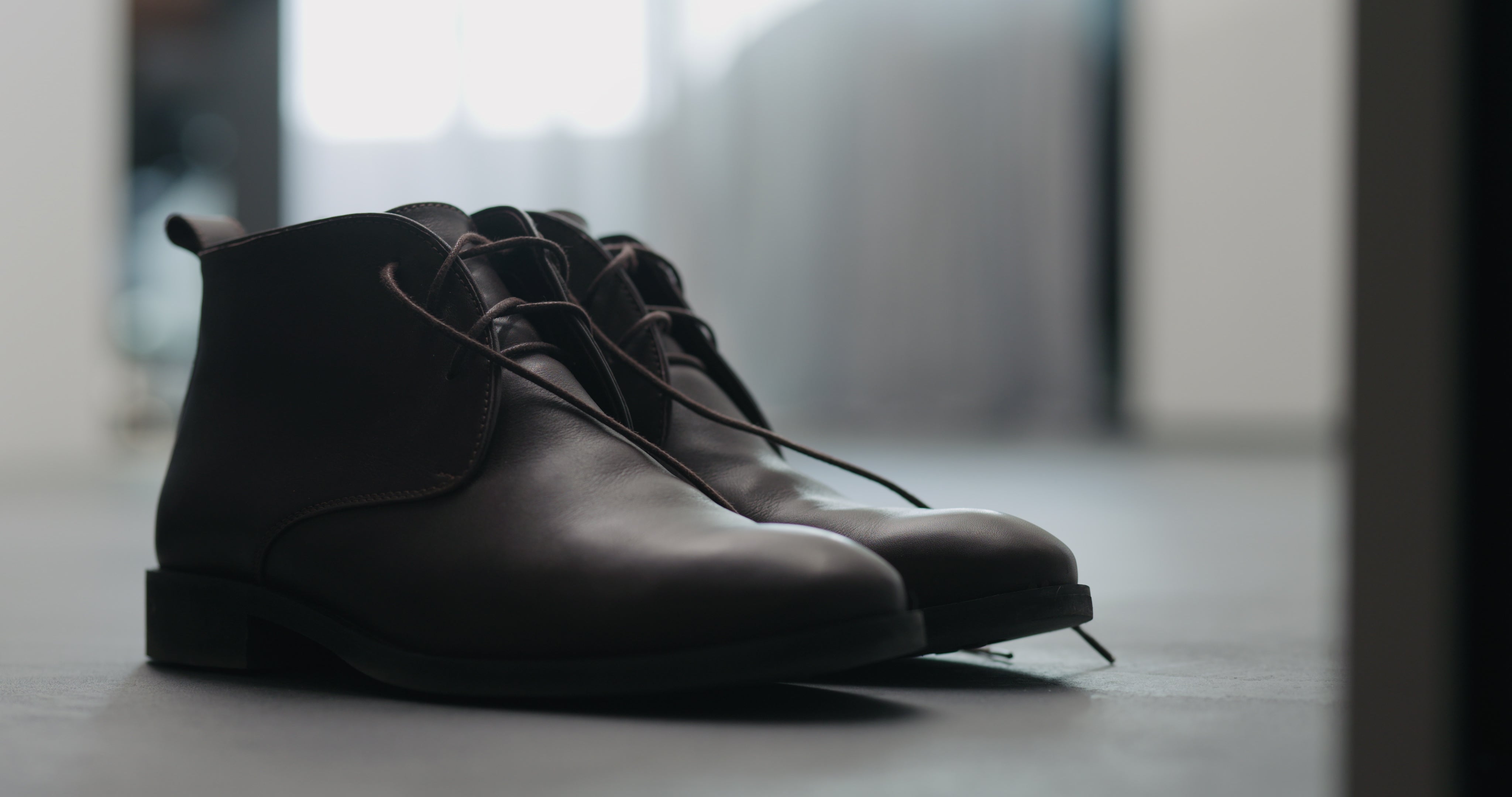 A pair of black chukka boots in the foreground against a modern, stylish backdrop.