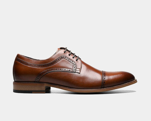 A Cap Toe Oxford shoe in a cognac color, featuring a lace-up closure, cap toe, and a stacked heel.