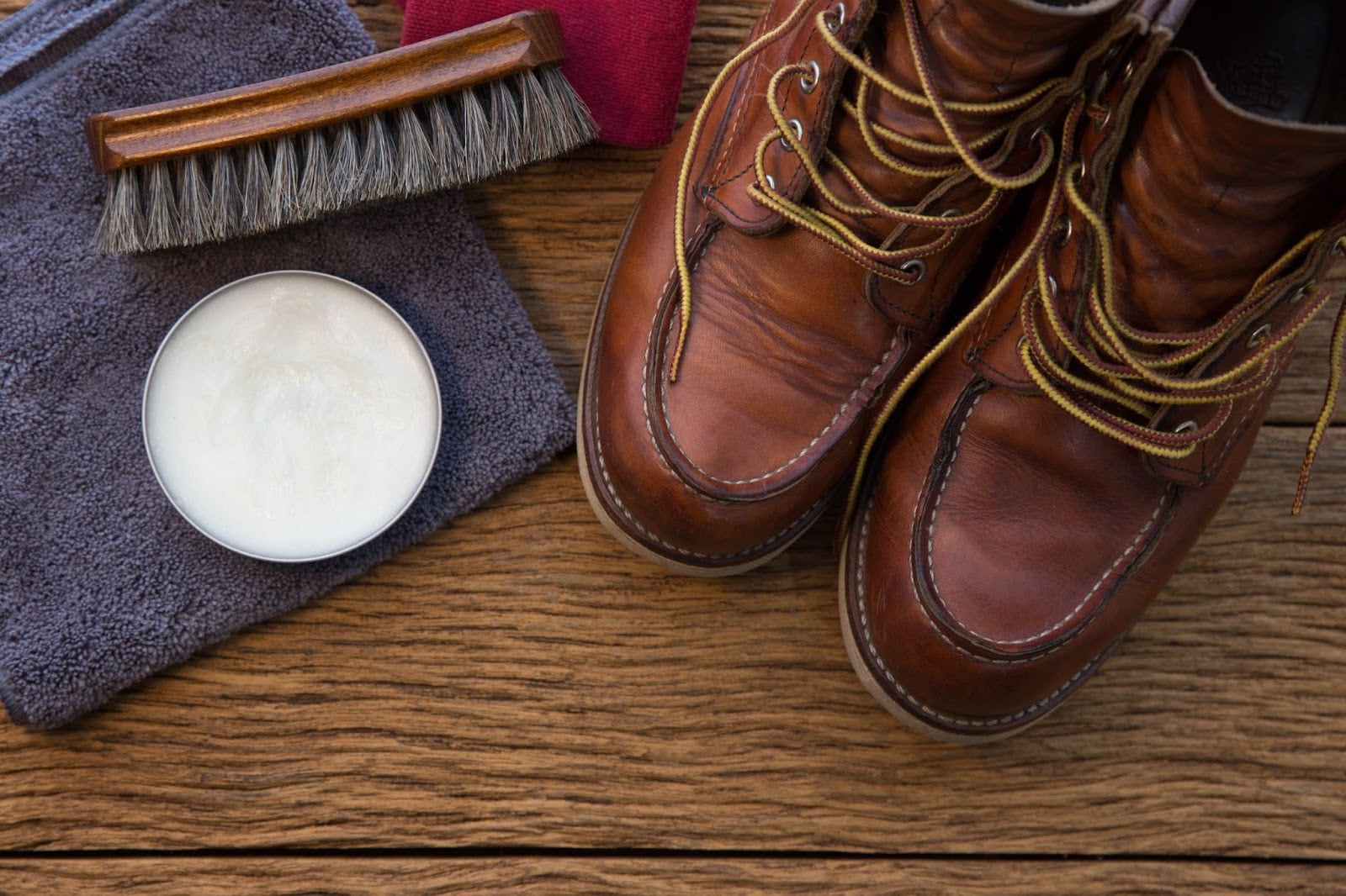 Clean Leather Boots with brush and cloth on wood floor.