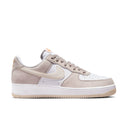 Nike Air Force 1 '07 sneakers in white and light beige suede with perforated toe box and rubber sole, side view.