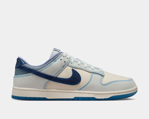 Nike Dunk Low Retro SE sneakers in cream and blue with a textured leather and mesh upper, blue stitched details, and blue outsole, side view.