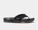 A black Reef brand flip flop with a synthetic nubuck upper and a herringbone rubber outsole, featuring a built-in bottle opener.