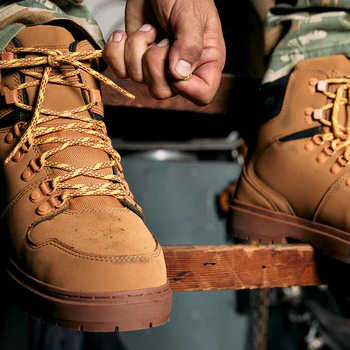 "DC WorkCrew Peary TR Work Waterproof Comp Toe Boot in tan leather with yellow laces and rugged outsole, lifestyle view of person tying shoelace"